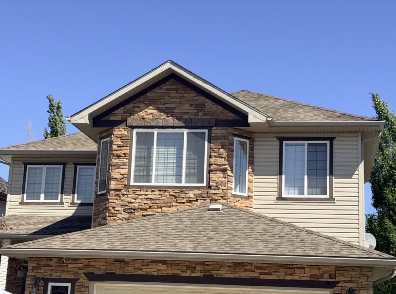 Two-storey Calgary home with an asphalt shingle roof on a clear day