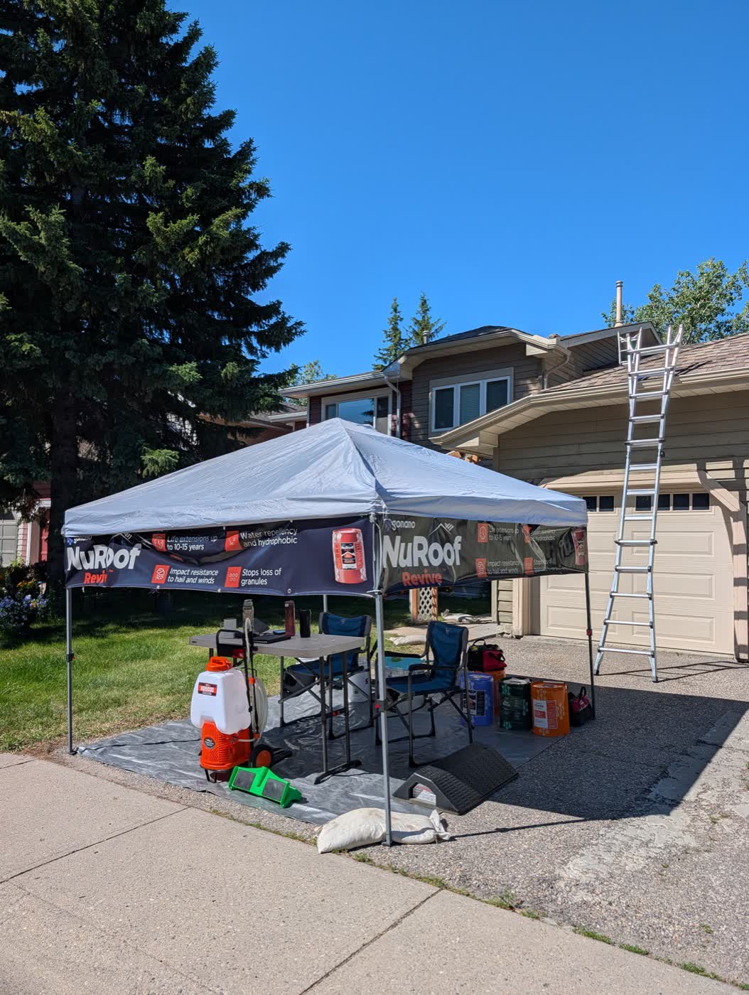 Nano Shield job site in Calgary with branded NuRoof tent, sprayer and ladder